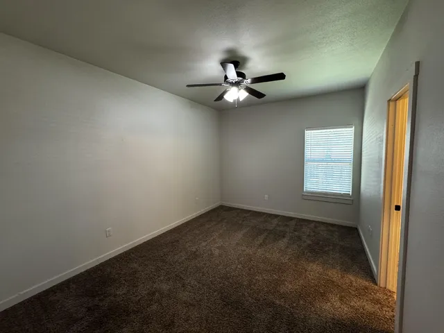 an empty room with a window and a ceiling fan