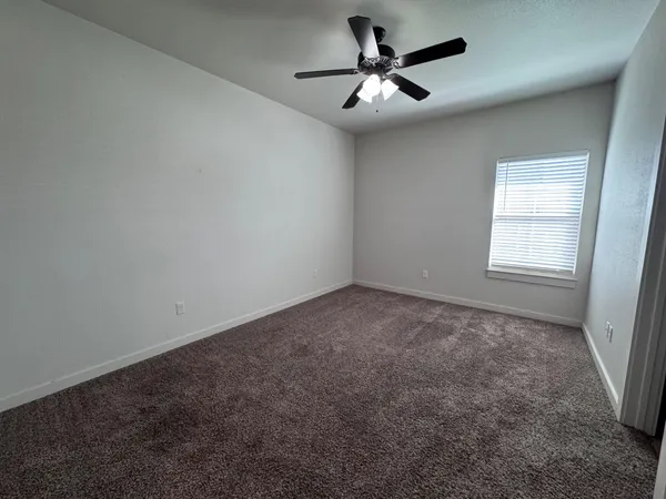 an empty room with a chandelier fan and windows
