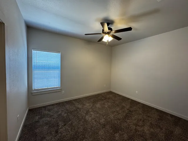 an empty room with a window and a fan