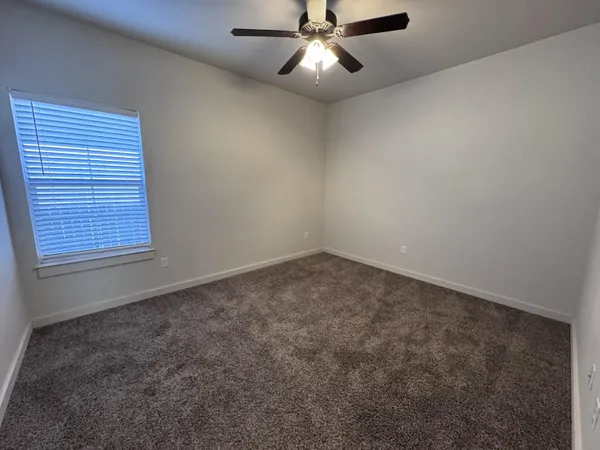 an empty room with a window and a fan