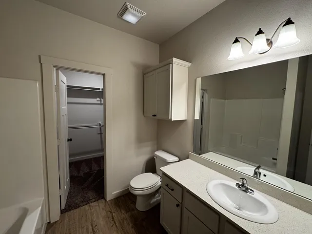 a bathroom with a toilet a sink a light fixture and a mirror