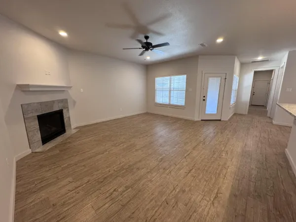 an empty room with wooden floor fireplace and windows