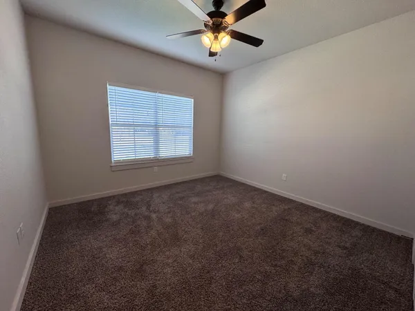 an empty room with a window and a fan