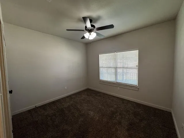 an empty room with a window and a fan