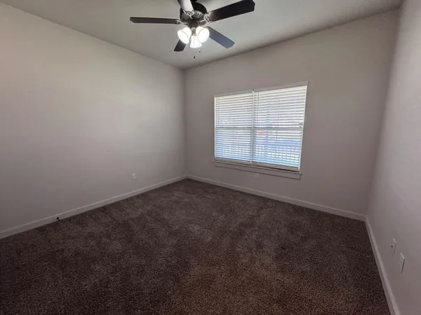 an empty room with a window and a fan