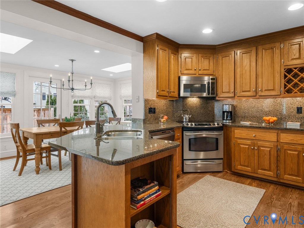 8101 Longwood Road Henrico, VA 23229 - Photo 13 of 49 a kitchen with stainless steel appliances granite countertop a stove top oven a sink dishwasher a dining table and chairs with wooden floor