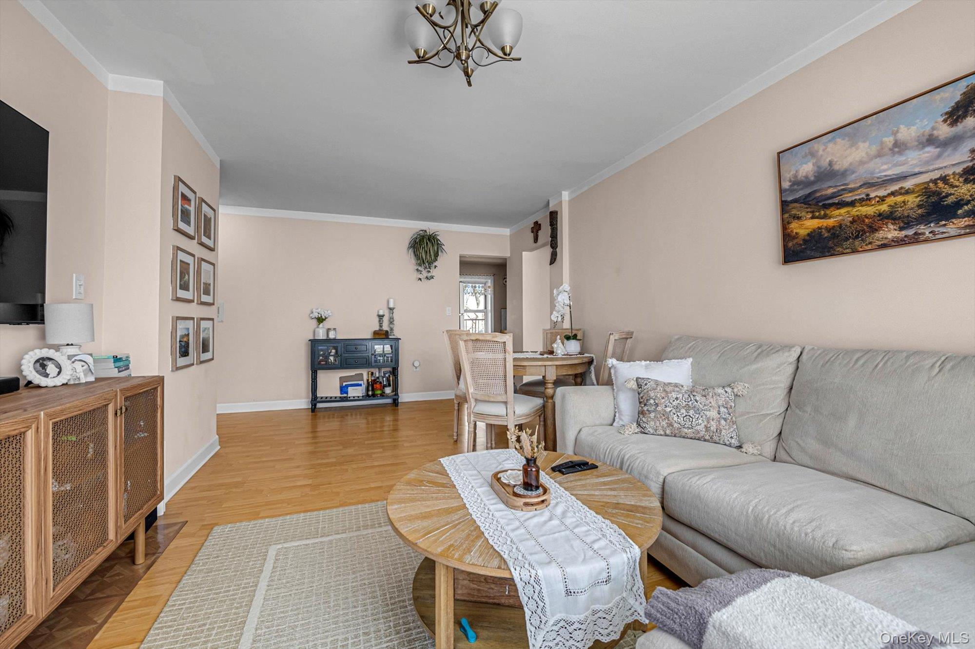 141-45 78th Road, Unit 3A Queens, NY 11367 - Photo 3 of 17 Living room with light wood-type flooring, crown molding, baseboards, and a notable chandelier