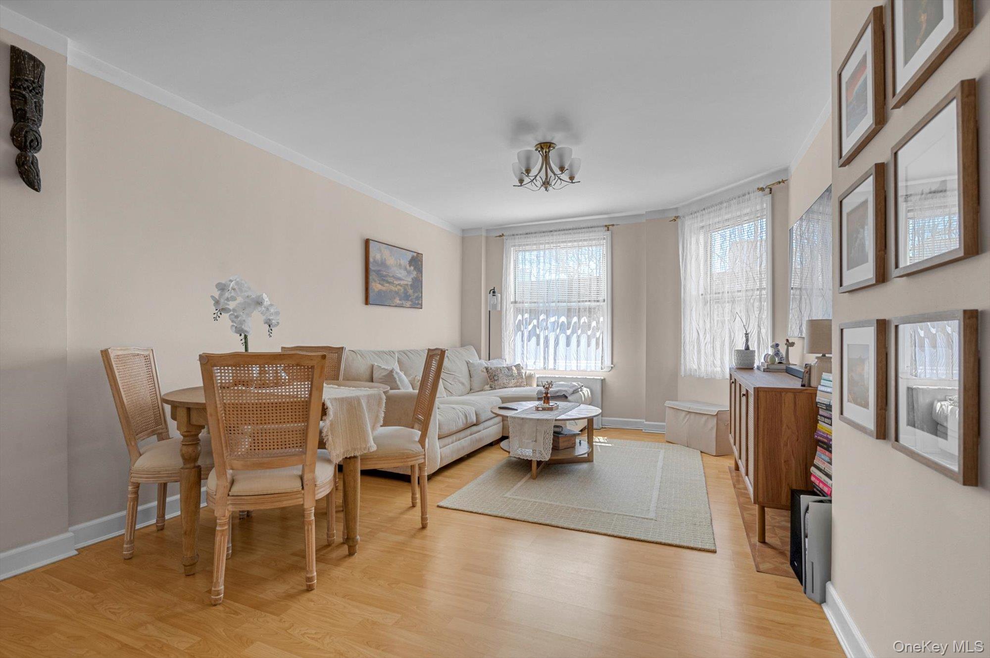 141-45 78th Road, Unit 3A Queens, NY 11367 - Photo 4 of 17 Living area featuring light wood-style floors, ornamental molding, baseboards, and a notable chandelier