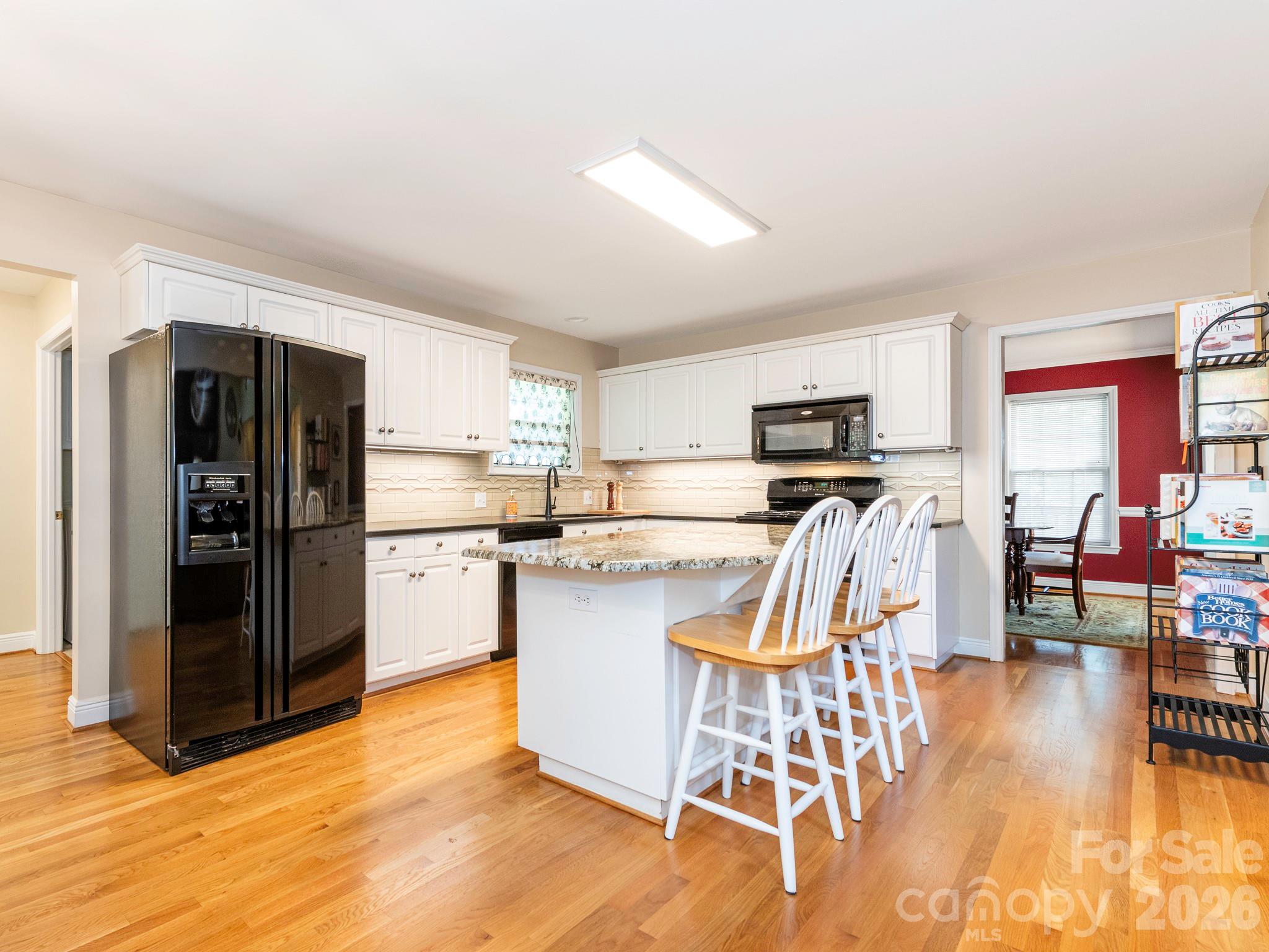 4440 Hucks Road Charlotte, NC 28269 - Photo 11 of 45 a kitchen with stainless steel appliances granite countertop a refrigerator a stove top oven a sink dishwasher and white cabinets with wooden floor