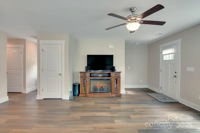 an empty room with wooden floor a ceiling fan and a window