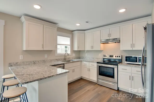 a kitchen with granite countertop white cabinets and white appliances
