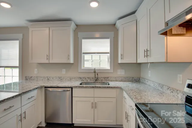 a kitchen with granite countertop white cabinets white stainless steel appliances and a sink