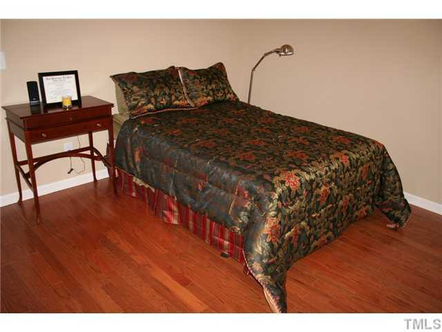 7862 Cape Charles Drive Raleigh, NC 27617 - Photo 11 of 12 a bedroom with a bed and wooden floor