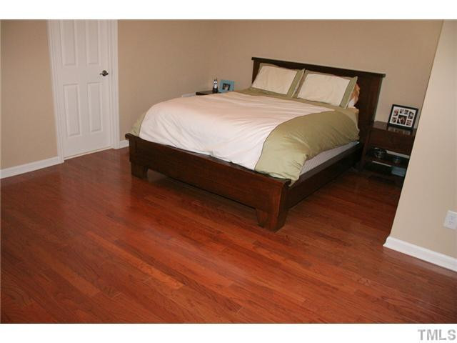 7862 Cape Charles Drive Raleigh, NC 27617 - Photo 9 of 12 a spacious bedroom with a bed and wooden floor