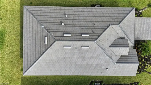 a view of a house with yard and a car park in front of it