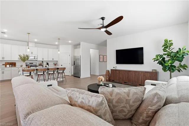 a living room with furniture kitchen view and a flat screen tv