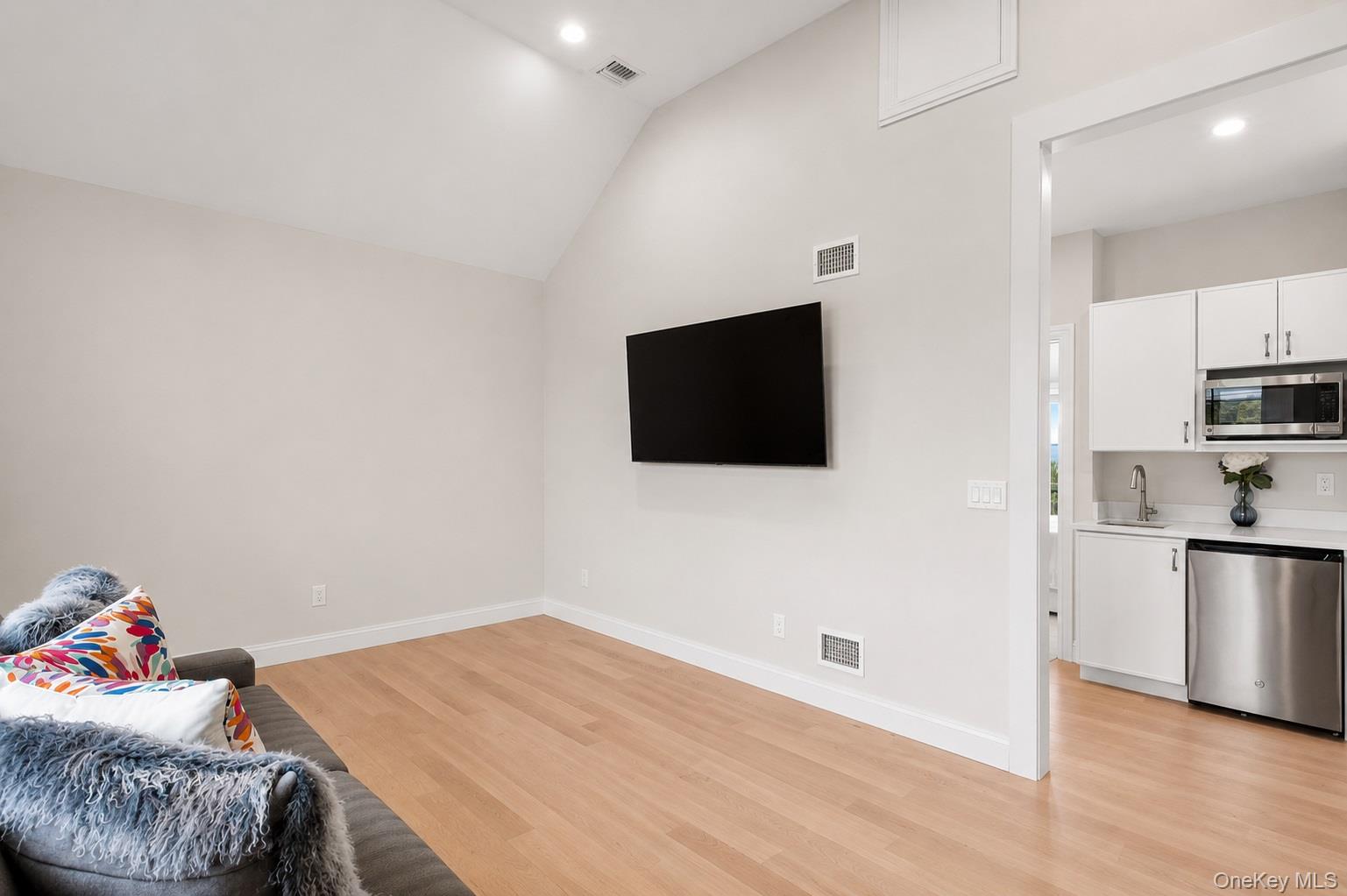 65 Shore Road Westhampton, NY 11977 - Photo 13 of 24 Vaulted ceiling with recessed lighting, wood-finish flooring, and a wall-mounted television