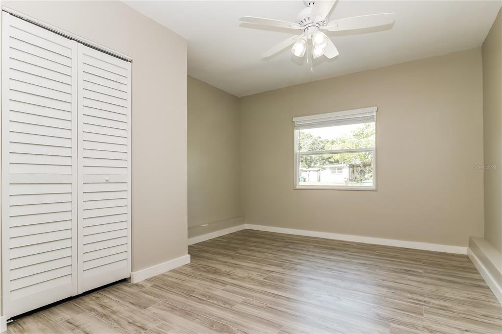 9537 Groveland Street Seminole, FL 33772 - Photo 7 of 16 an empty room with wooden floor chandelier fan and windows