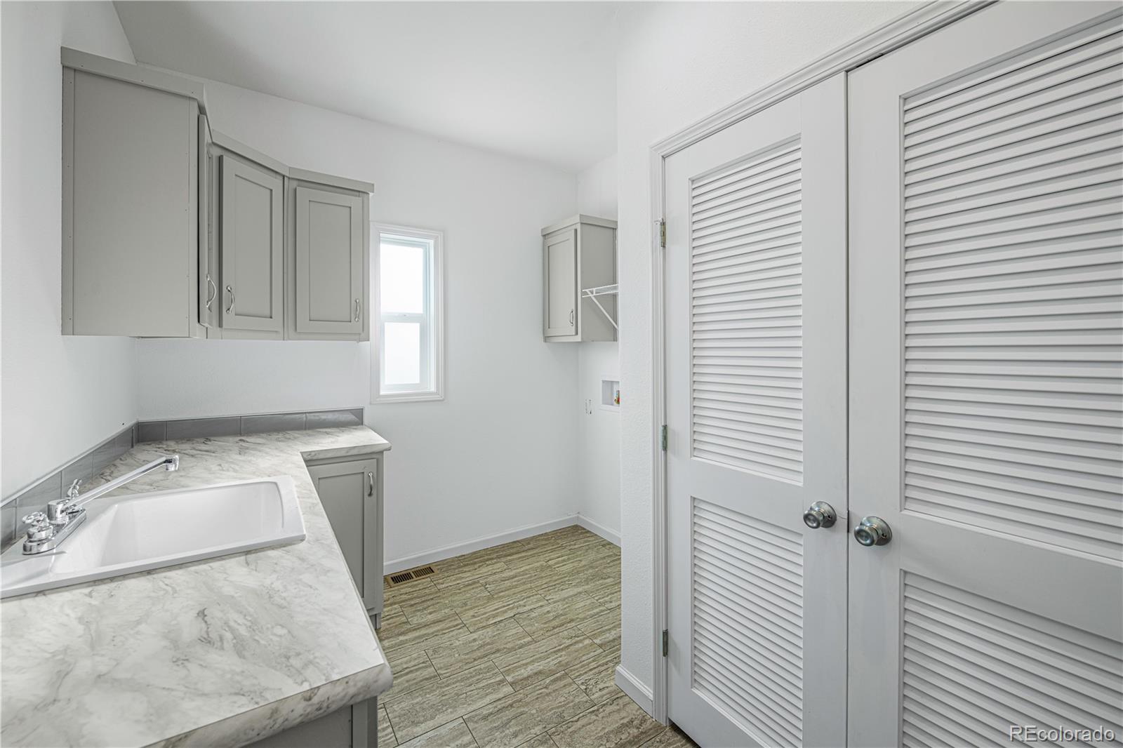 6 Timberlake Road Byers, CO 80103 - Photo 13 of 18 a room with a washing machine and wooden floor