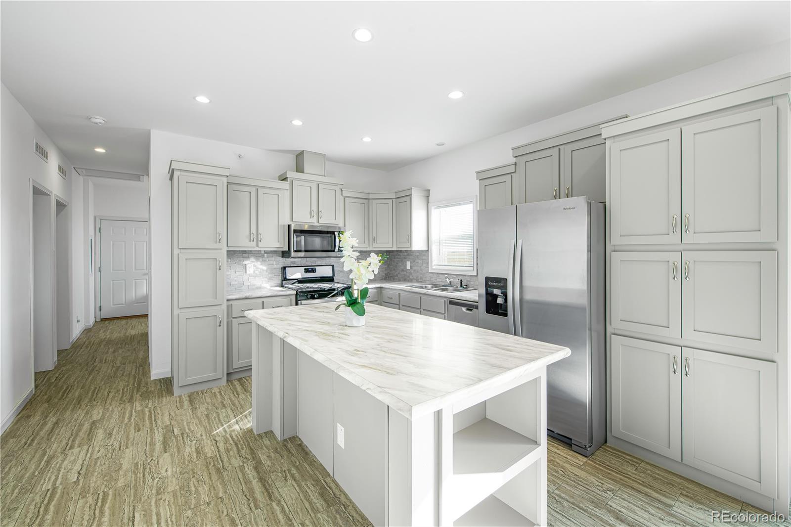 6 Timberlake Road Byers, CO 80103 - Photo 7 of 18 a kitchen with a refrigerator a sink and wooden floor