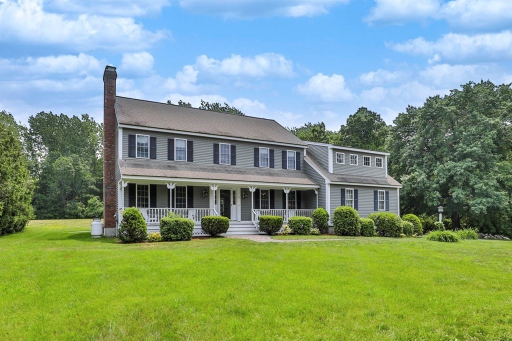 a front view of a house with garden and trees
