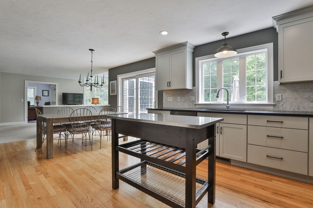 4 Breezy Point Road Acton, MA 01720 - Photo 5 of 40 a kitchen with stainless steel appliances granite countertop wooden floor dining table and chairs