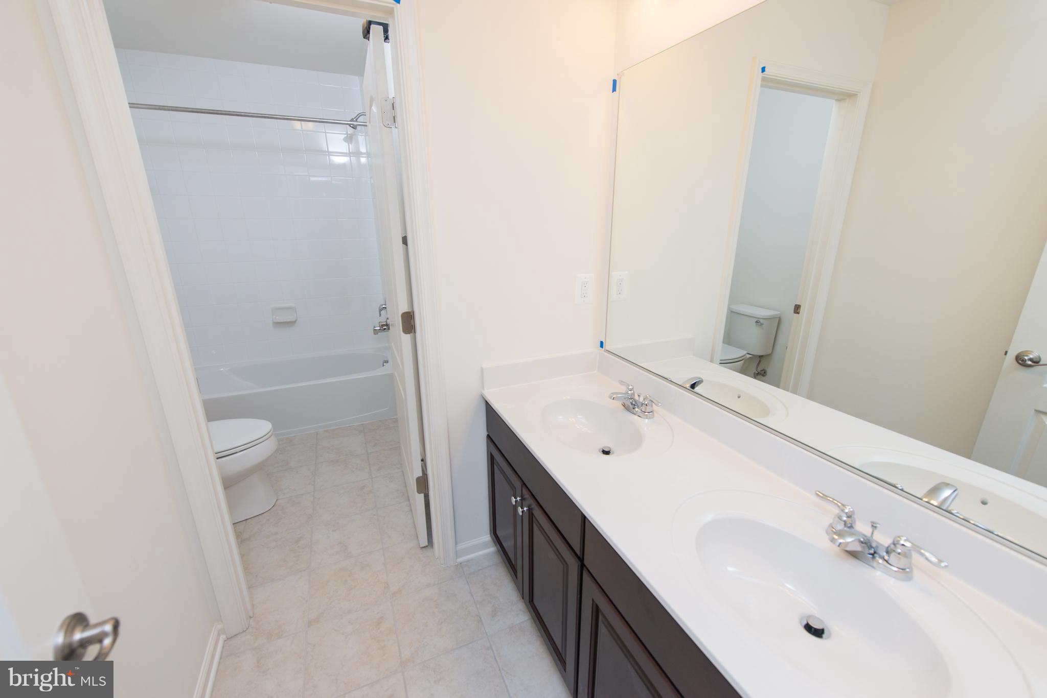 910 Ramble Run Road Baltimore, MD 21220 - Photo 16 of 30 a spacious bathroom with a double vanity sink toilet and shower