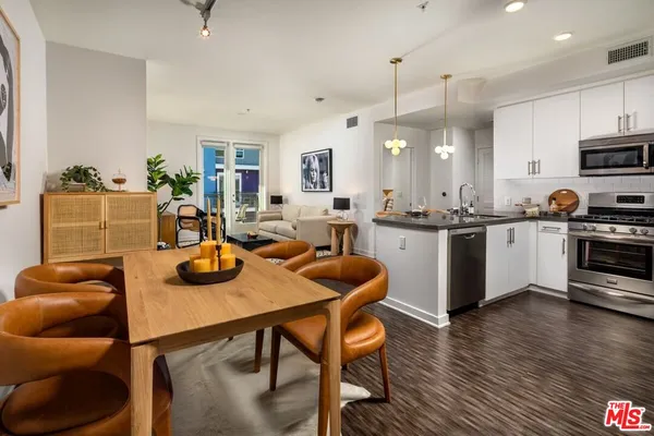 a kitchen with stainless steel appliances granite countertop a sink a stove a dining table and chairs