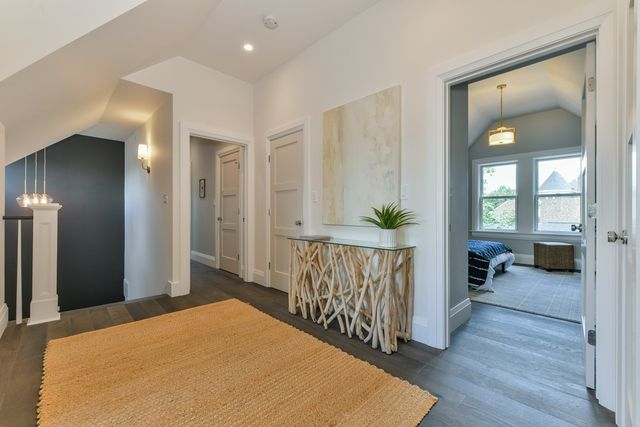 a view of a hallway to a livingroom with wooden floor and furniture