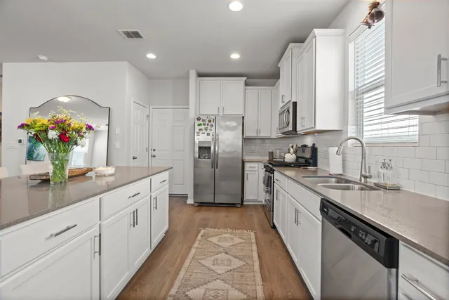 a kitchen with stainless steel appliances granite countertop a sink counter space cabinets and a large window