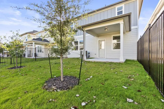 a view of a house with a big yard and large tree