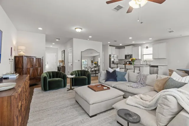 a living room with furniture kitchen view and a chandelier