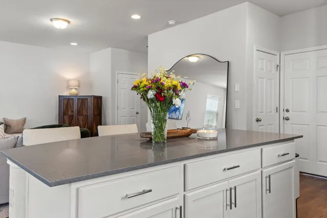 a kitchen with kitchen island granite countertop a sink and white cabinets