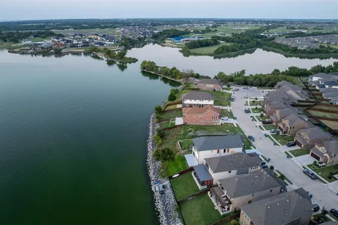 a view of a white house next to a yard with big trees
