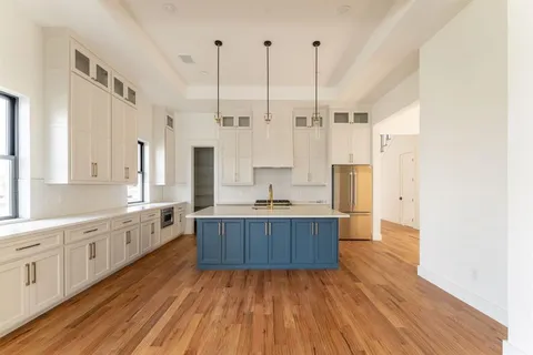 a large kitchen with kitchen island white cabinets and stainless steel appliances