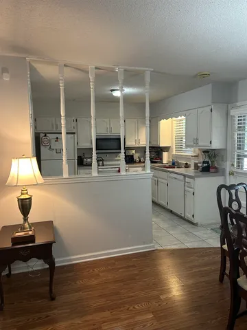 a kitchen with stainless steel appliances kitchen island granite countertop a table chairs in it and wooden floors