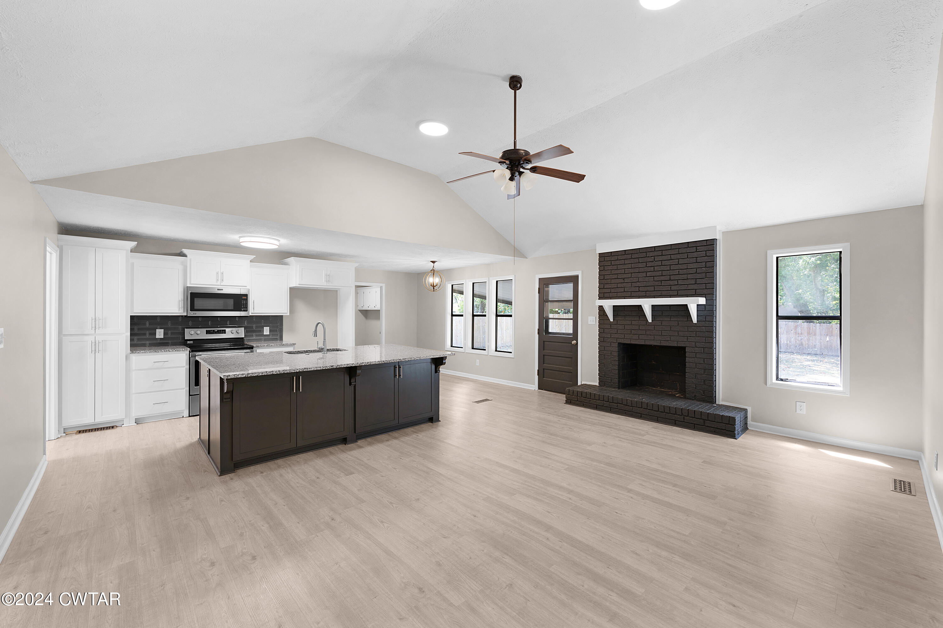 117 Ridgeoak Place Jackson, TN 38305 - Photo 13 of 20 a large kitchen with stainless steel appliances kitchen island a stove a refrigerator a oven and a fireplace with wooden floor