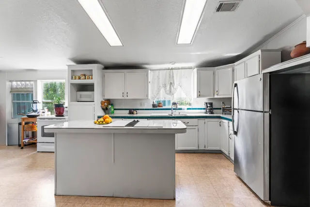 a kitchen with stainless steel appliances a refrigerator a sink a stove and white cabinets