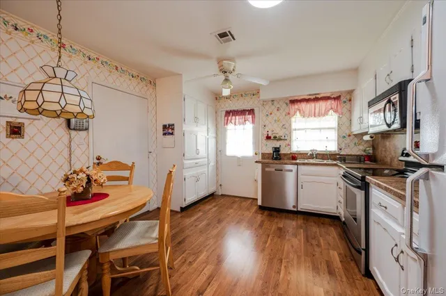 a kitchen with stainless steel appliances granite countertop a stove a sink dishwasher and a refrigerator with wooden floor