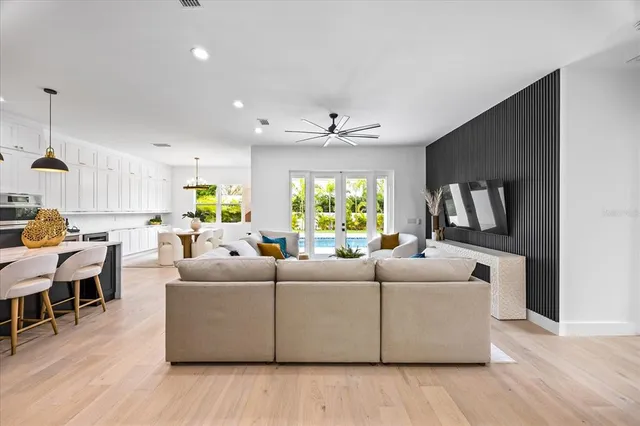 a kitchen with stainless steel appliances kitchen island granite countertop a stove a sink a refrigerator and a dining table with wooden floor