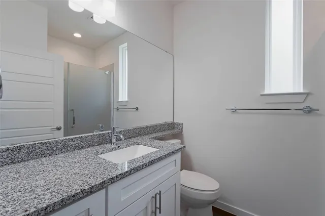a bathroom with a granite countertop sink a toilet and a mirror