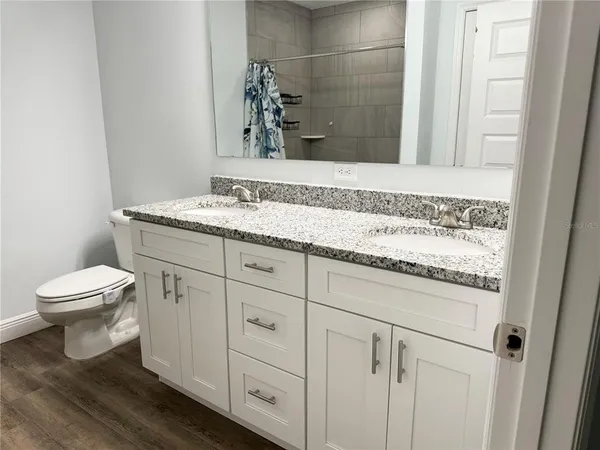 a bathroom with a granite countertop toilet sink and mirror