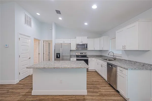 a large kitchen with stainless steel appliances lots of counter space and wooden floor