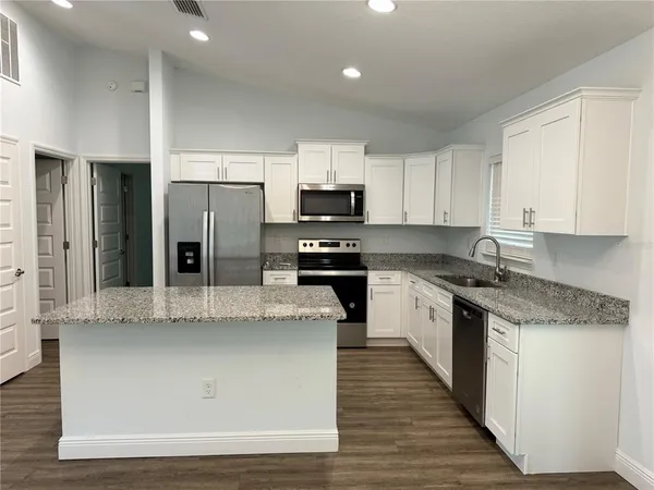 a kitchen with stainless steel appliances granite countertop a stove a sink and a refrigerator