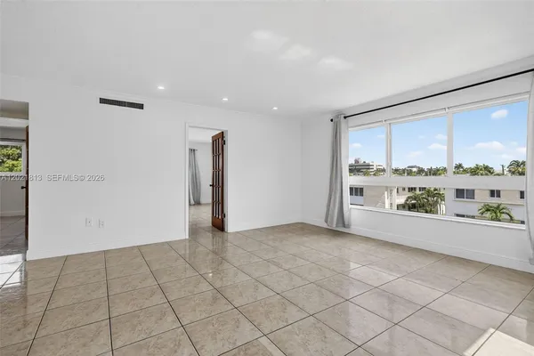 an empty room with kitchen view and natural light