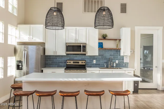 a kitchen with stainless steel appliances granite countertop a sink dishwasher a microwave oven a stove and a dining table with wooden floor