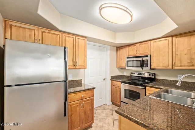 a kitchen with stainless steel appliances granite countertop a refrigerator a stove a sink and a microwave