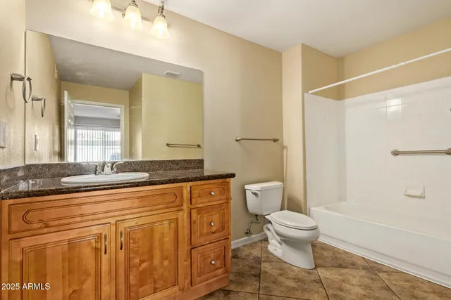 a bathroom with a granite countertop sink a toilet a mirror and shower