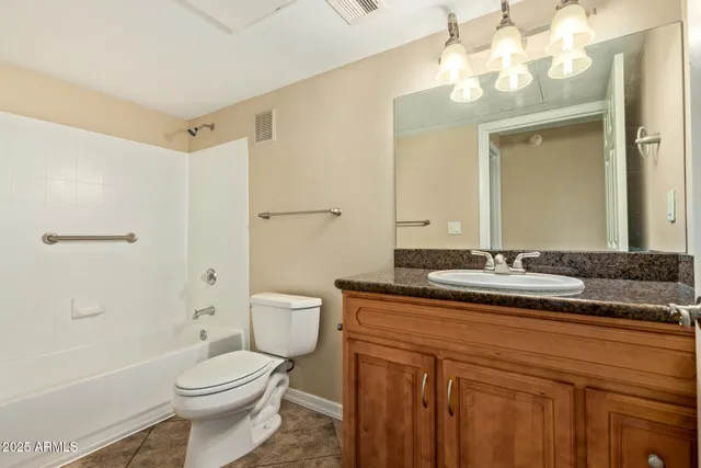 a bathroom with a granite countertop sink a toilet mirror and shower