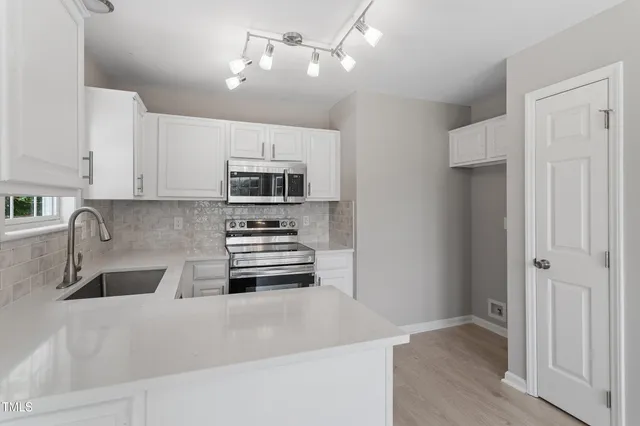 a kitchen with stainless steel appliances a stove a sink and white cabinets